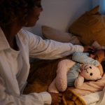 A tender moment of a mother tucking her child in for a cozy night's sleep with a teddy bear.