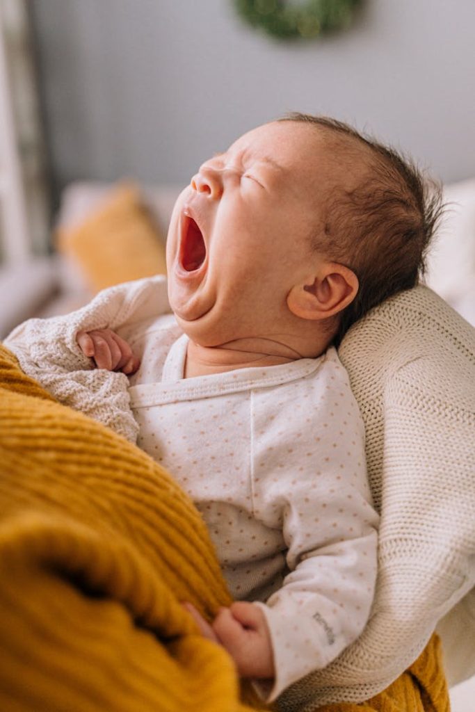 Close-up portrait of a yawning baby in a warm blanket. Perfect for parenting and lifestyle themes.