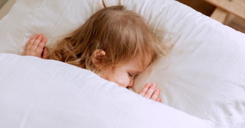 A young child peacefully sleeping under white blankets, embodying innocence and serenity.